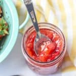 overhead of strawberry vanilla jam in a jar with a spoon scooping