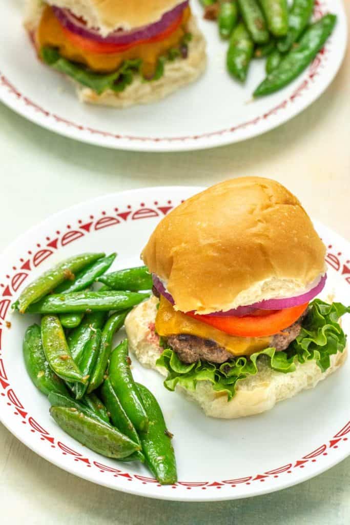 bison burger on a plate with sautéed snap peas