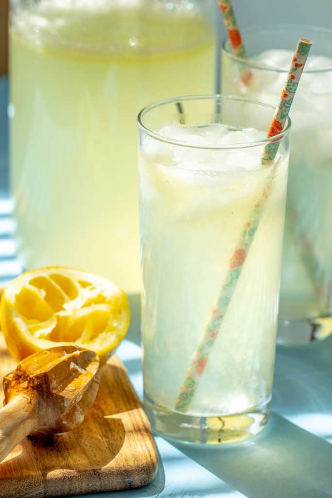 glasses of lemonade with paper straws and a citrus reamer beside