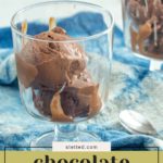 A glass cup brimming with chocolate frozen yogurt rests on a blue cloth, while another serving of this creamy treat appears in the background.
