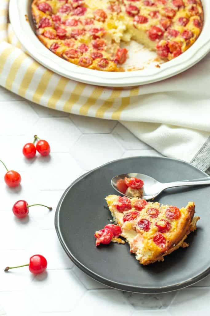 cherry clafoutis in a pie plate and served on a black plate