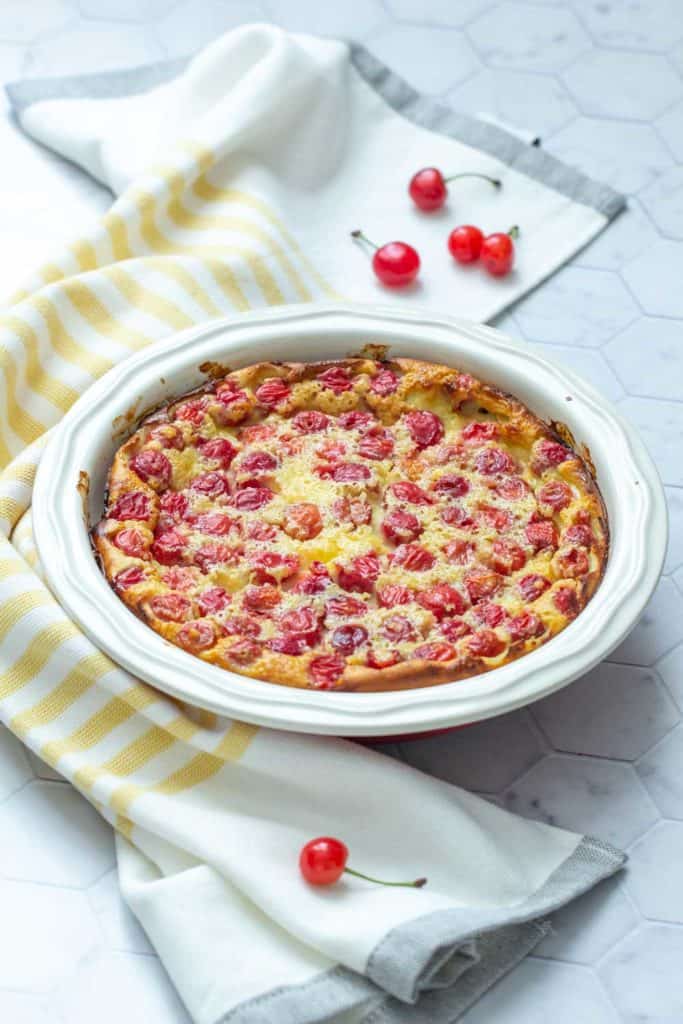 cherry clafoutis in a pie plate on a tile surface