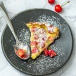 slice of cherry clafoutis on a black plate