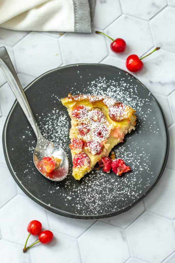 slice of cherry clafoutis on a black plate