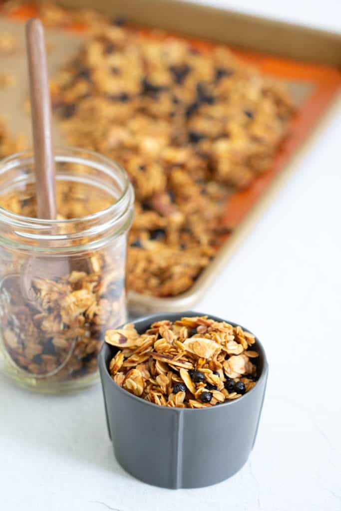 lemon blueberry granola in a gray bowl with a jar and sheet pan behind