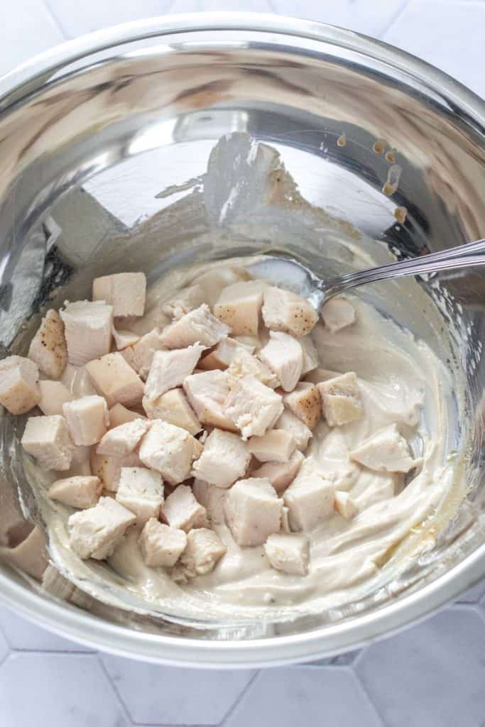 chicken being mixed into yogurt dressing