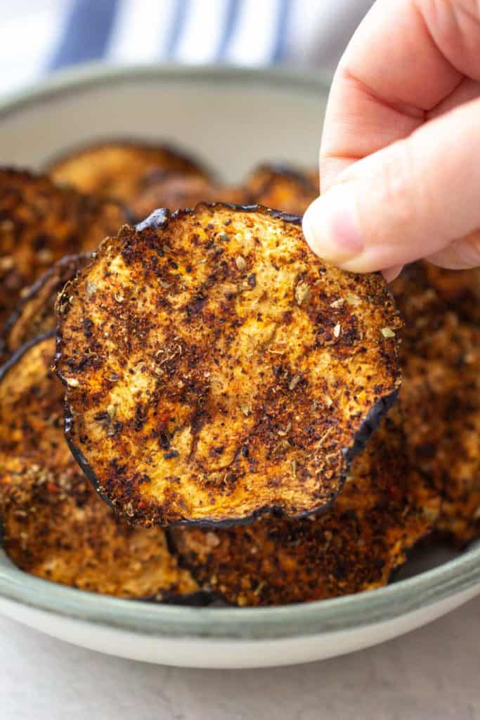 hand holding an eggplant chip