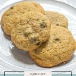 Four freshly baked zucchini chocolate chip cookies sit on a white plate, with a label at the bottom reading "zucchini chocolate chip cookies.