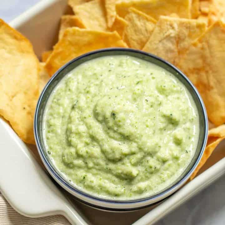 zucchini hummus in a bowl with pita chips aside