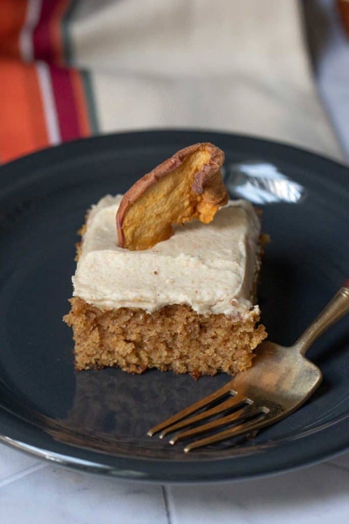 square of apple spice cake on black plate with fork