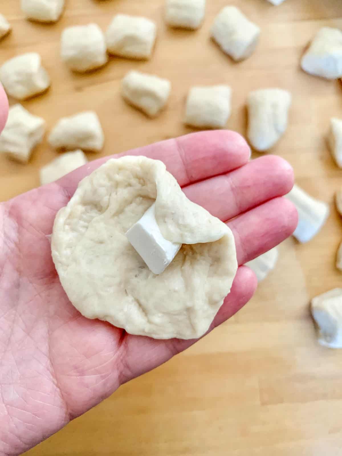hand filling pretzel bite dough with cheese