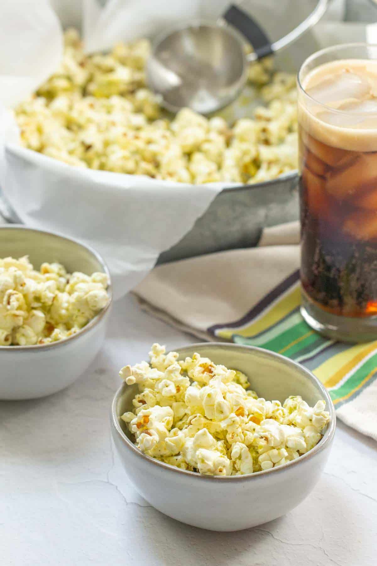 bowls of pesto popcorn with a soda