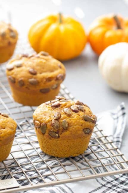 pumpkin muffins with spiced pepitas topping on a wire cooling rack
