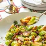 spooning up brussels sprouts with walnuts and cranberries