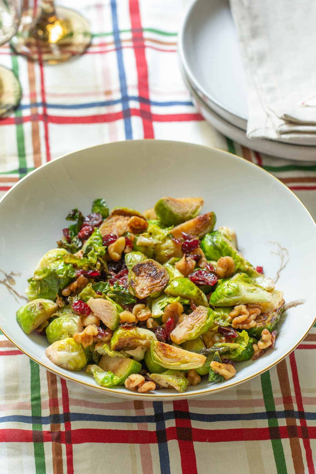bowl of brussels sprouts with walnuts and cranberries on plaid tablecloth