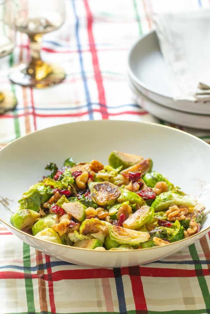 bowl of brussels sprouts with walnuts and cranberries on holiday table