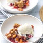 bowl of apple cranberry crisp with vanilla ice cream