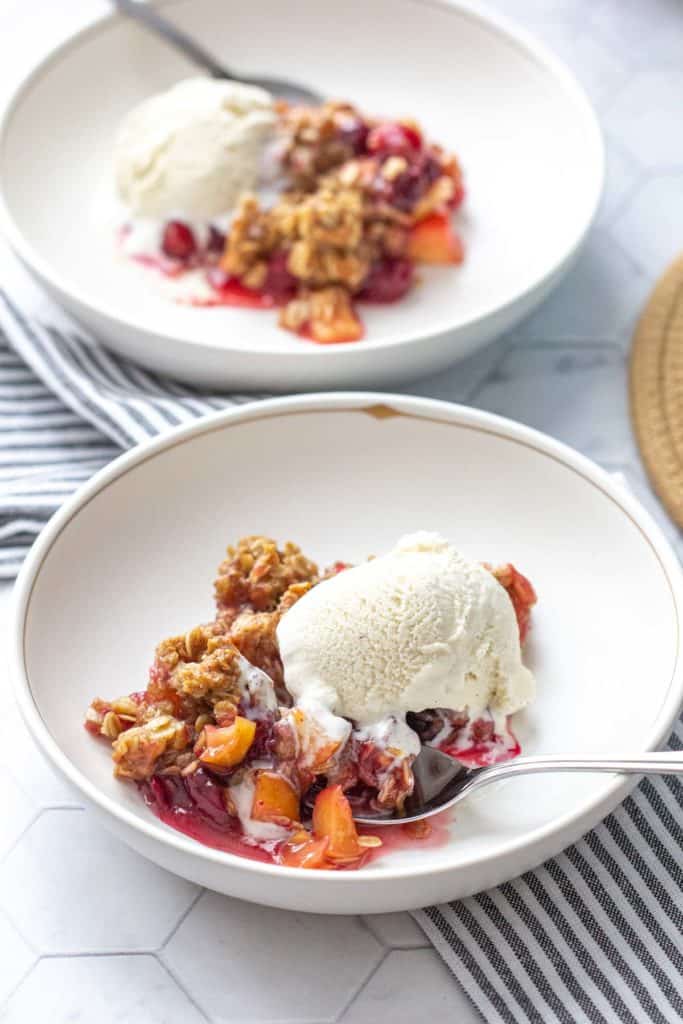 bowl of apple cranberry crisp with vanilla ice cream