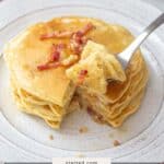 A stack of bacon pancakes with crispy bacon pieces sits on a white plate, one bite captured on a fork. Text overlay reads "bacon pancakes.