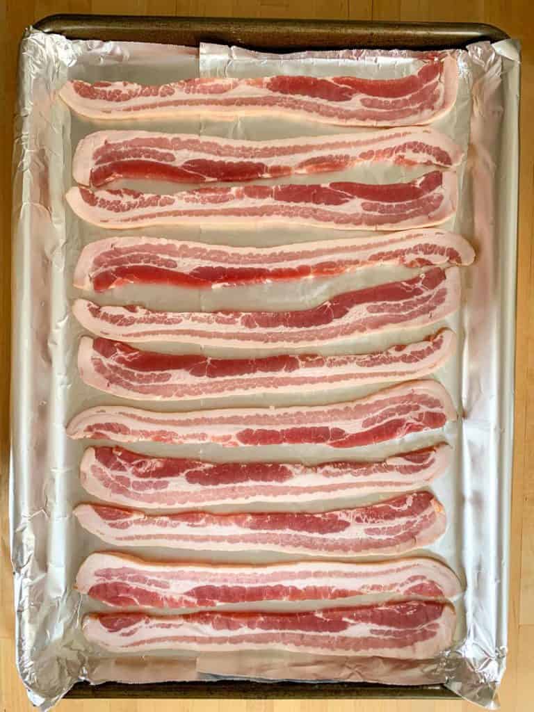 uncooked bacon on baking sheet