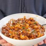 hands holding bowl of American goulash