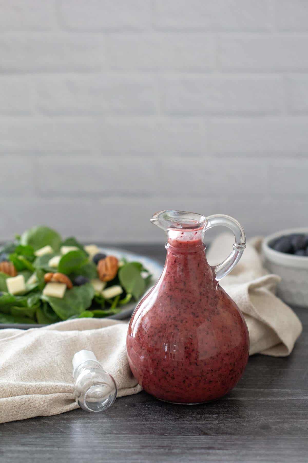 bottle of blueberry vinaigrette with salad behind