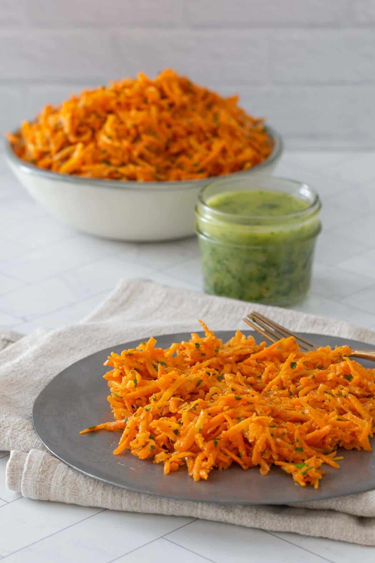 carrot salad on plate with bowl behind