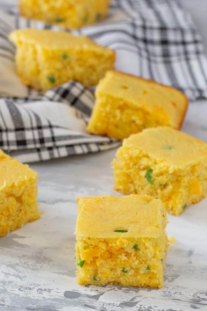 squares of jalapeno cornbread with cheese on a gray surface