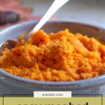A bowl of creamy mashed carrots with a spoon, lightly sprinkled with black pepper, sits on a table. Text on the image reads "easy mashed carrots.
