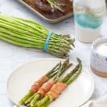 bacon wrapped asparagus with asparagus bundle behind