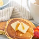 maple syrup being poured onto buttermilk pancakes