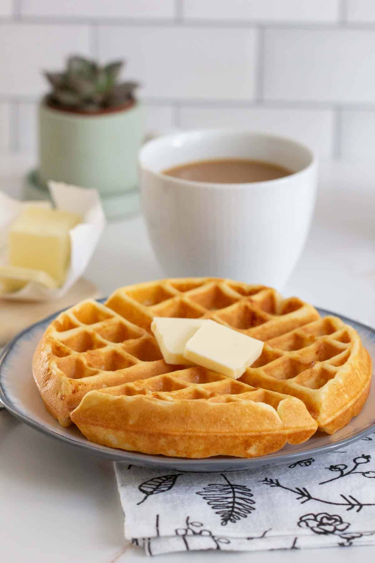 buttermilk waffle on plate with mug of coffee
