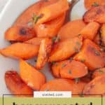Honey roasted carrots garnished with fresh herbs, served sliced in a white dish with a spoon.