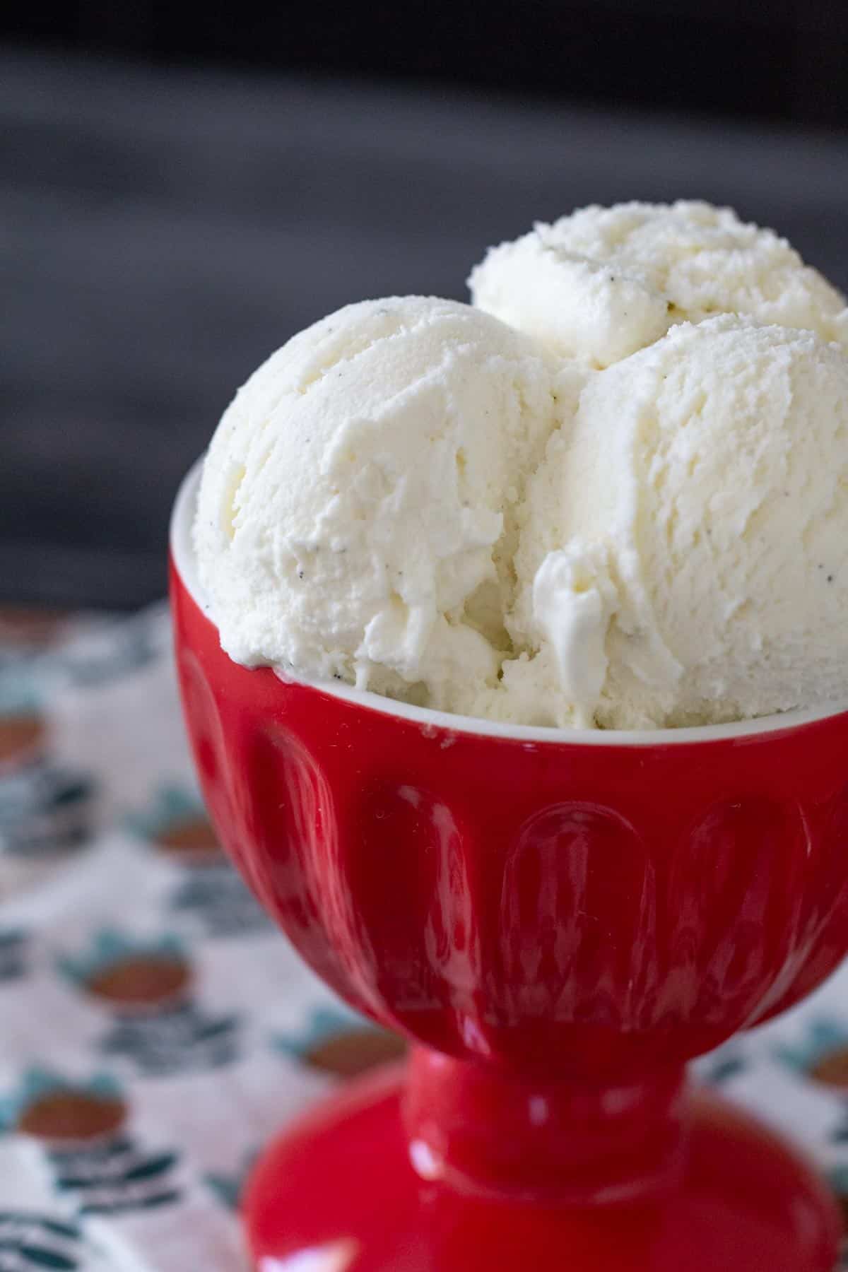 close up vanilla bean ice cream in red bowl