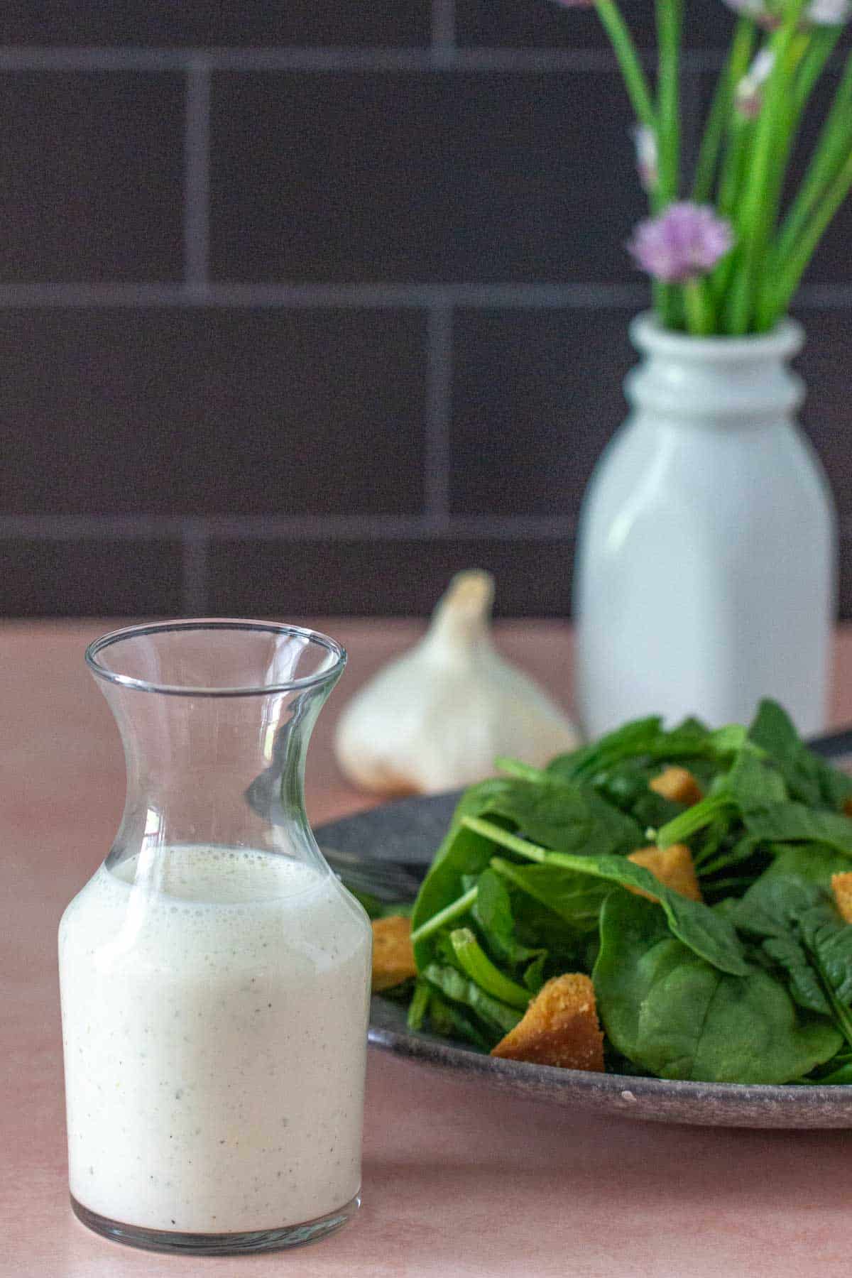 bottle of creamy garlic dressing with salad behind