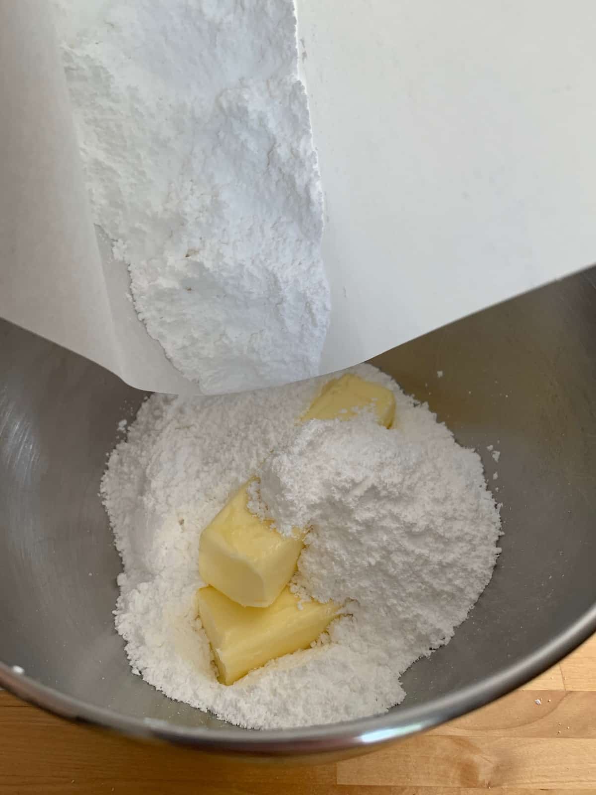 adding powdered sugar and butter to mixing bowl
