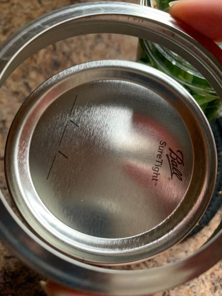 adding lid and ring to canning jar