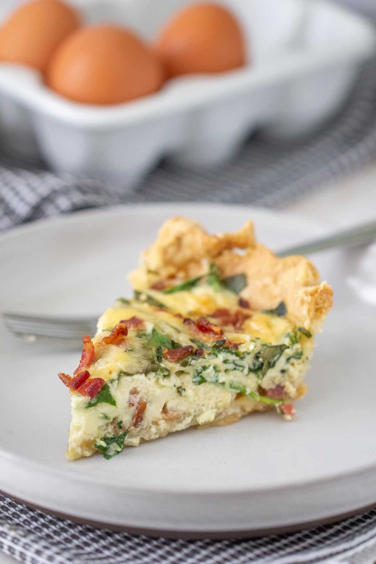 bacon spinach quiche slice on a gray plate