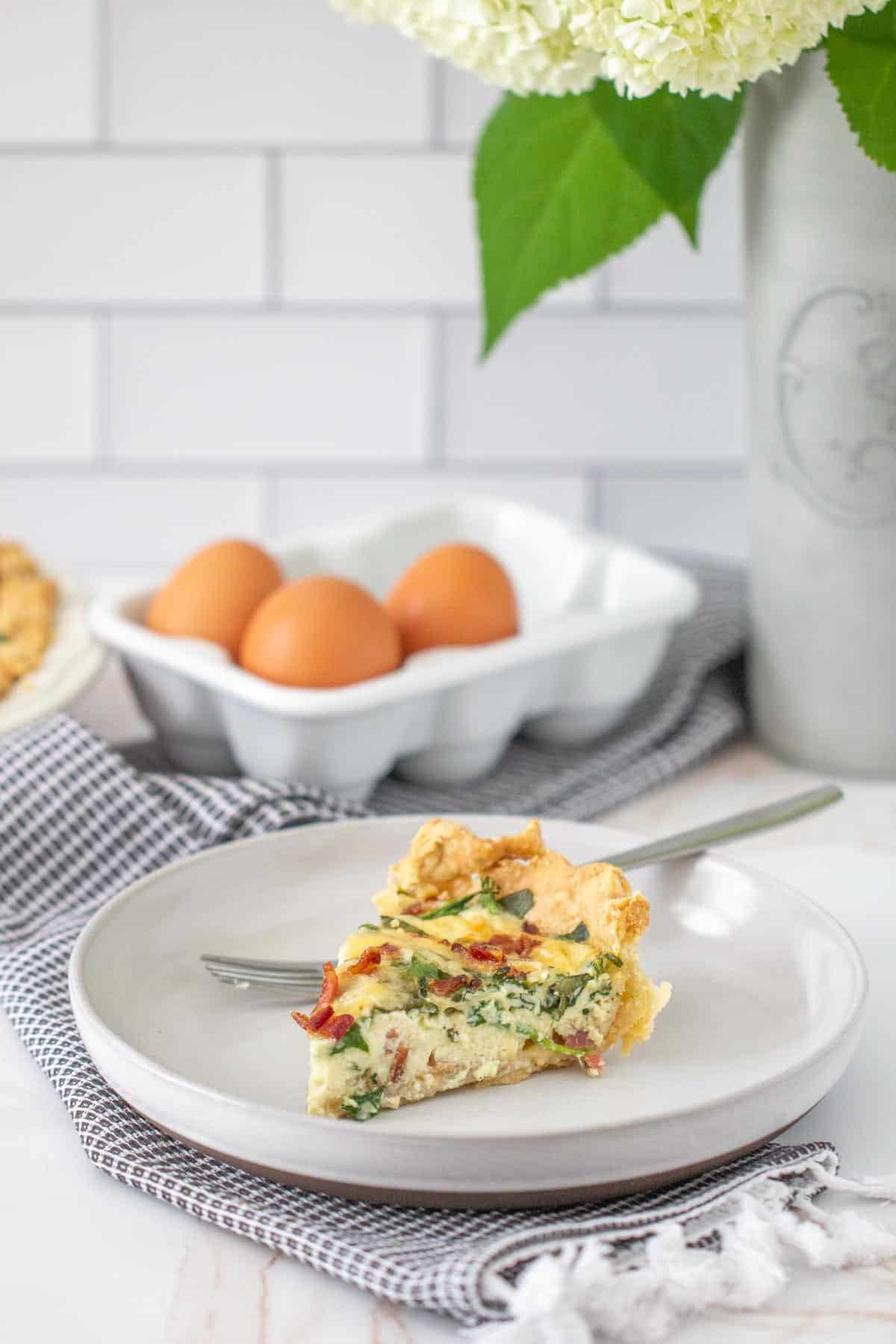 slice of bacon spinach quiche on a gray plate