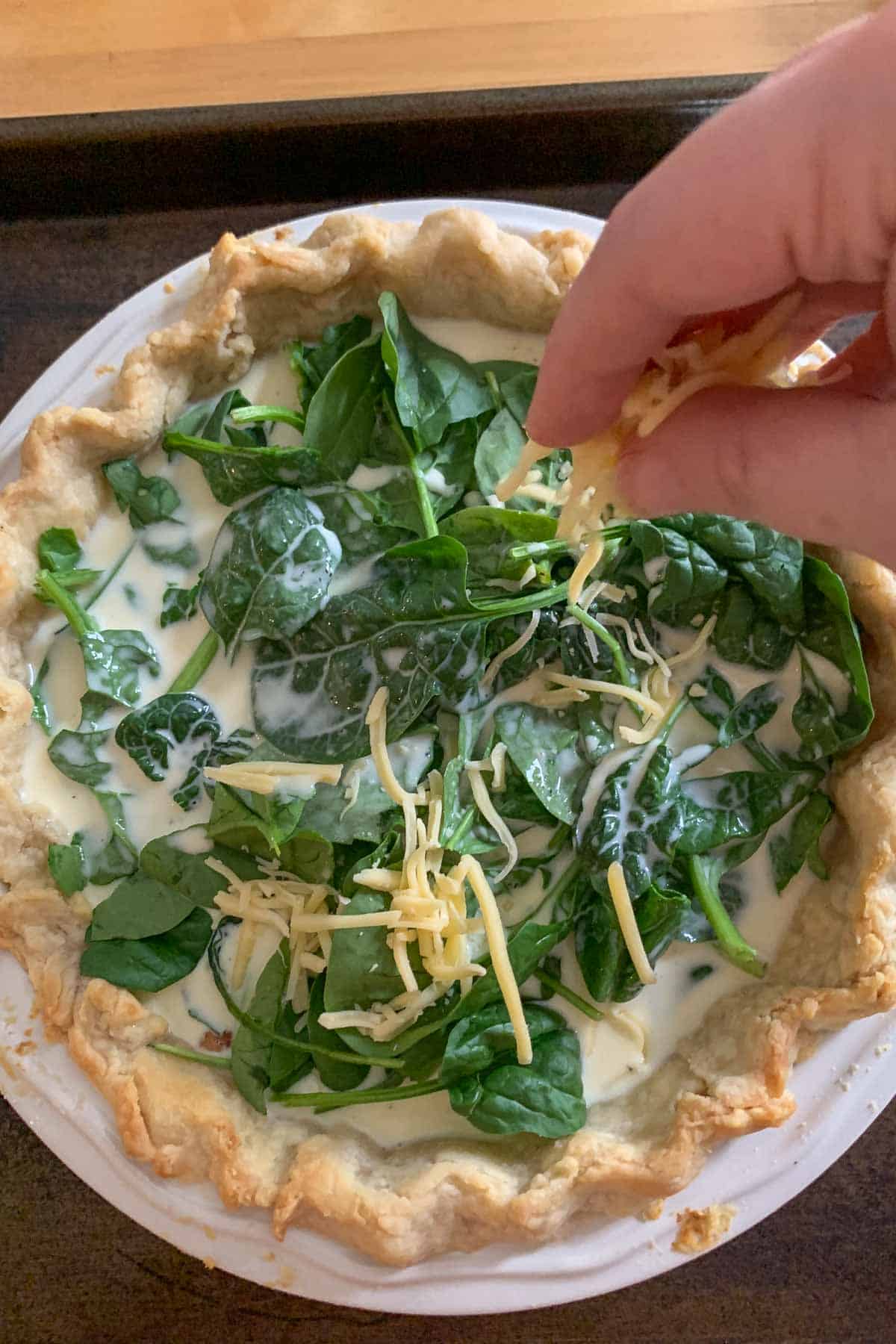 adding cheese to top of bacon spinach quiche