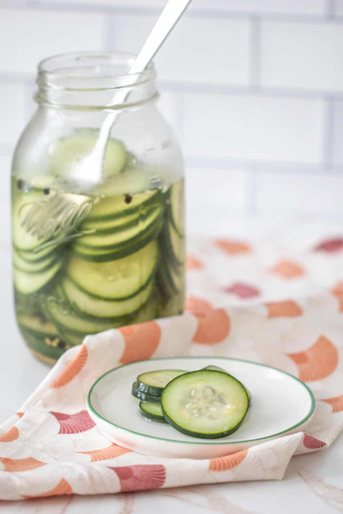 jar of quick pickled cucumbers with cucumbers on a plate