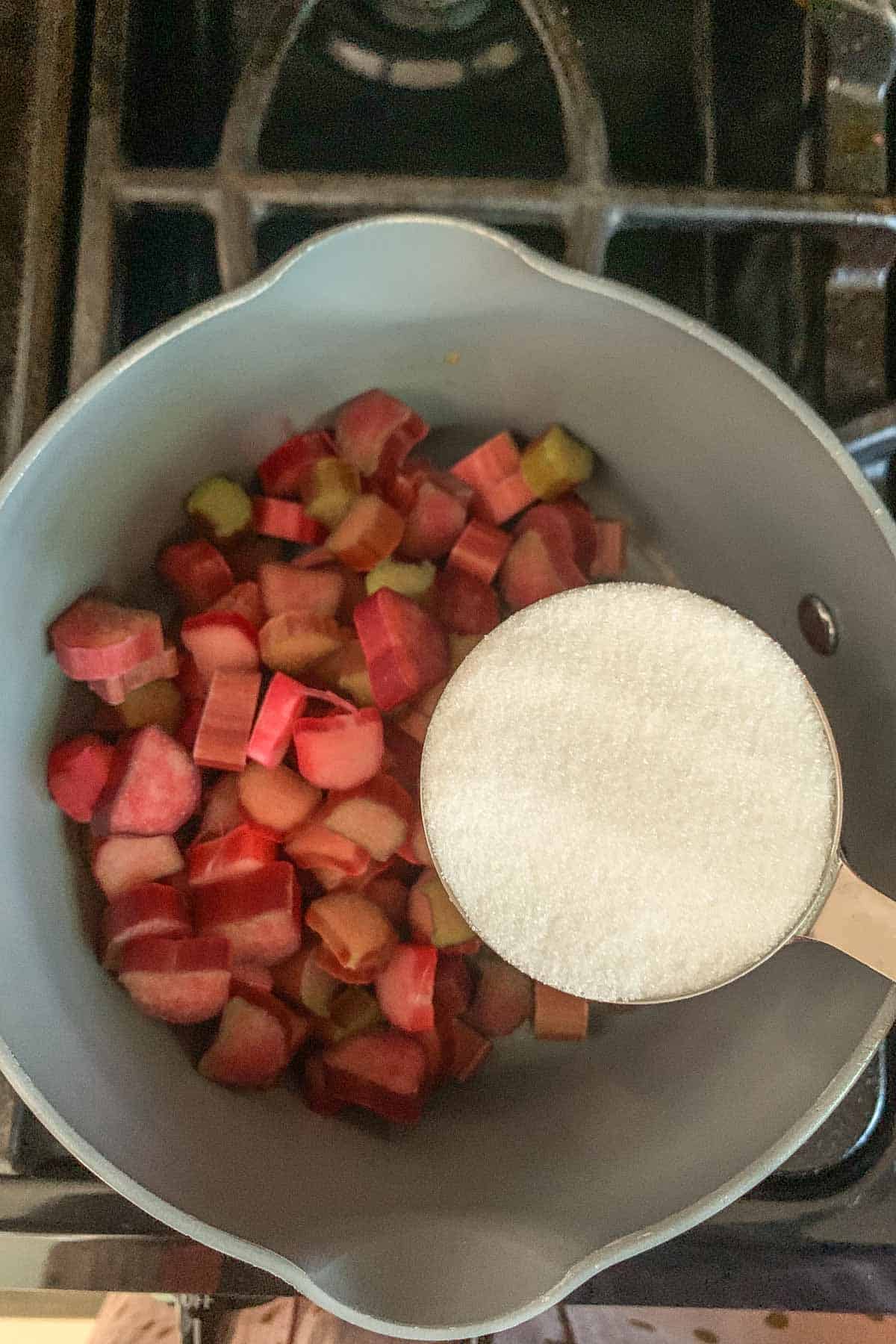 adding sugar to rhubarb in saucepan