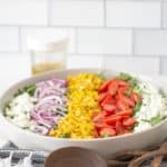 roasted corn salad in serving bowl with serving utensils