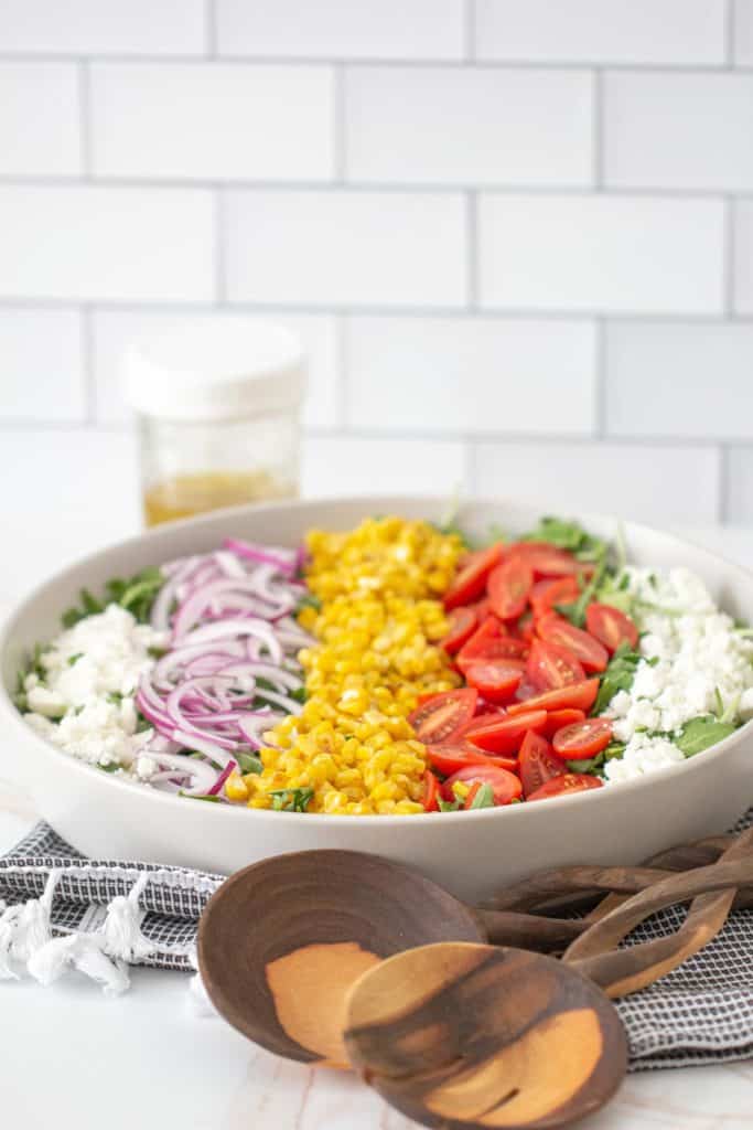 roasted corn salad in serving bowl with serving utensils