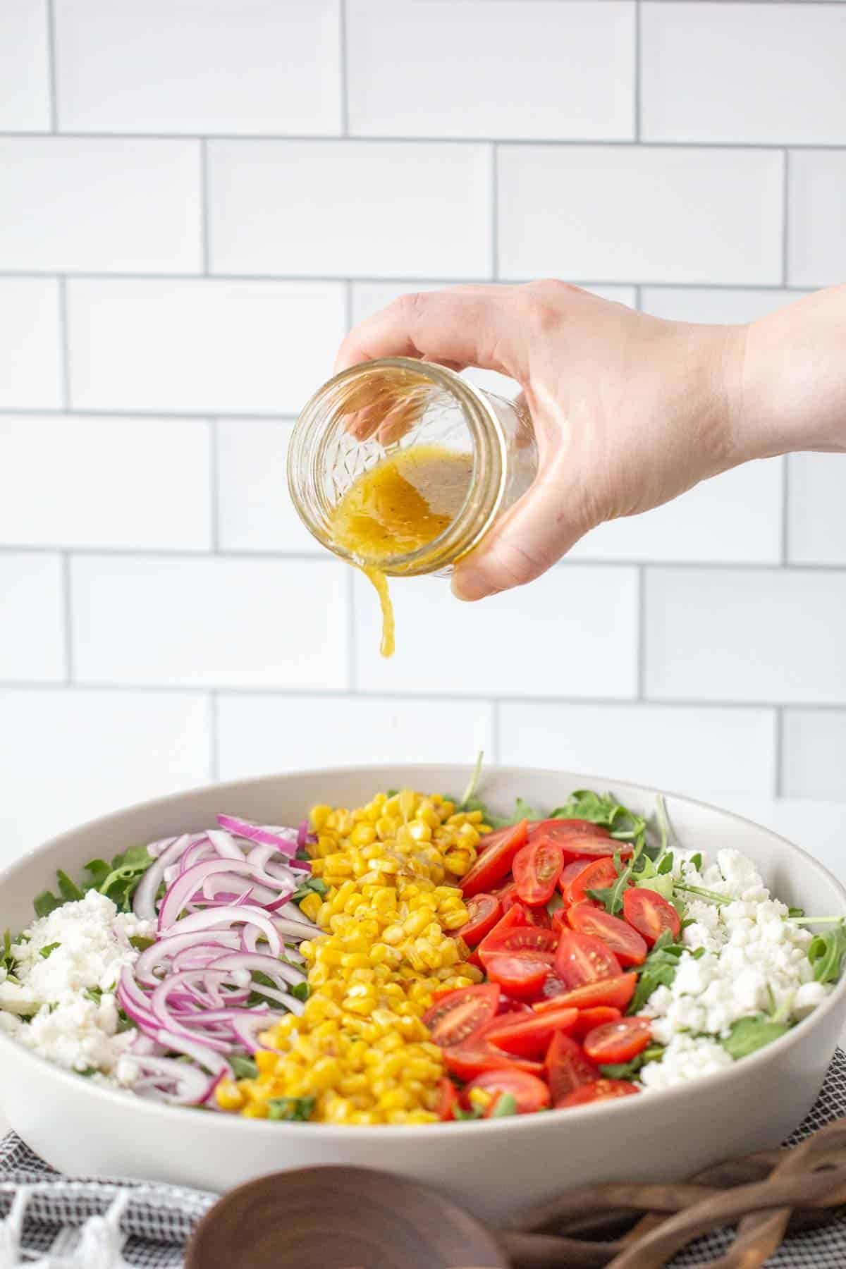 pouring dressing onto roasted corn salad