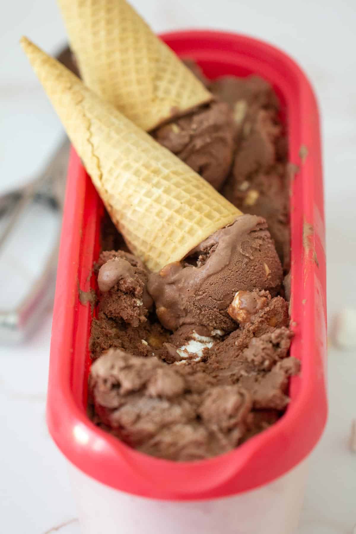 rocky road ice cream in a container with cones on top