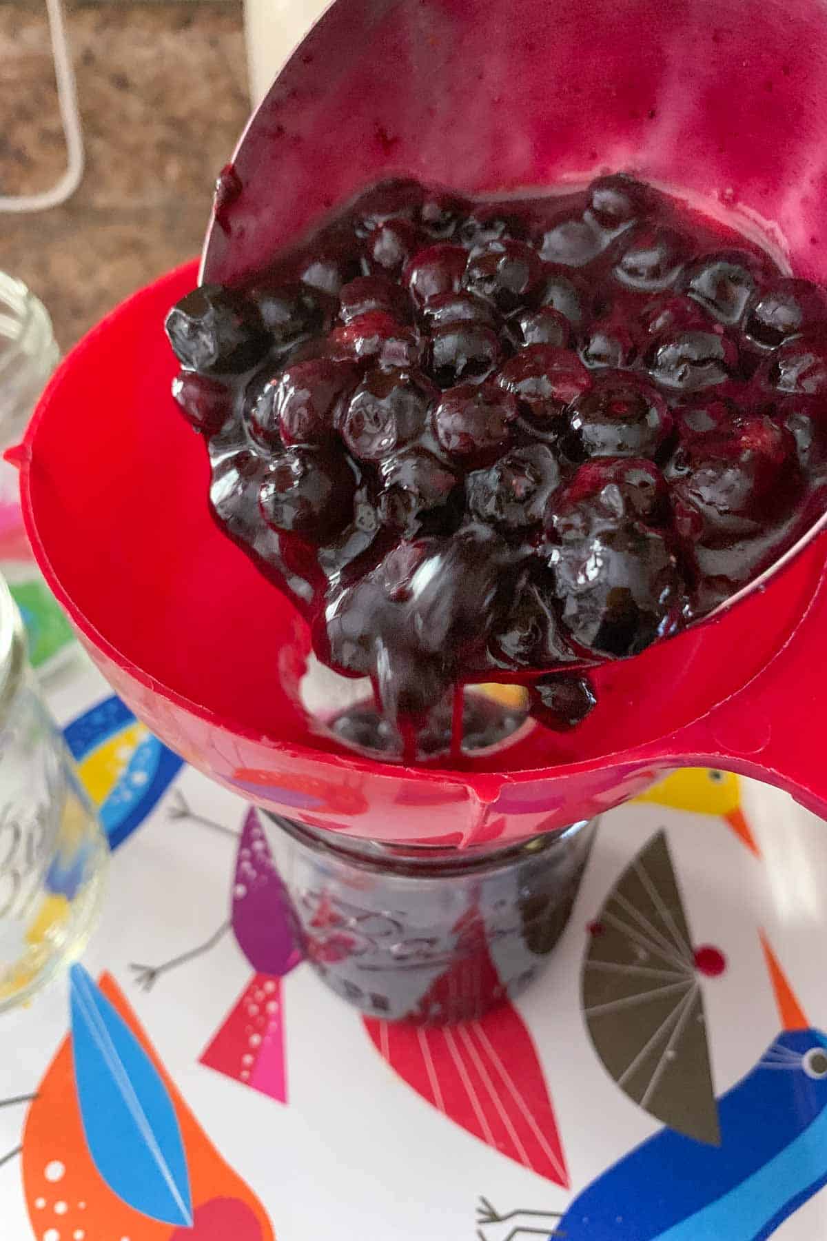 pouring blueberry pie filling into jars