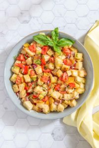 overhead of panzanella salad in a serving bowl with a yellow napkin