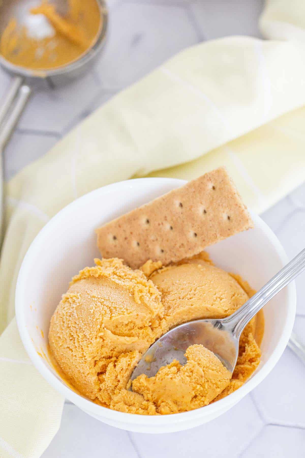 pumpkin ice cream in a white bowl with a spoon
