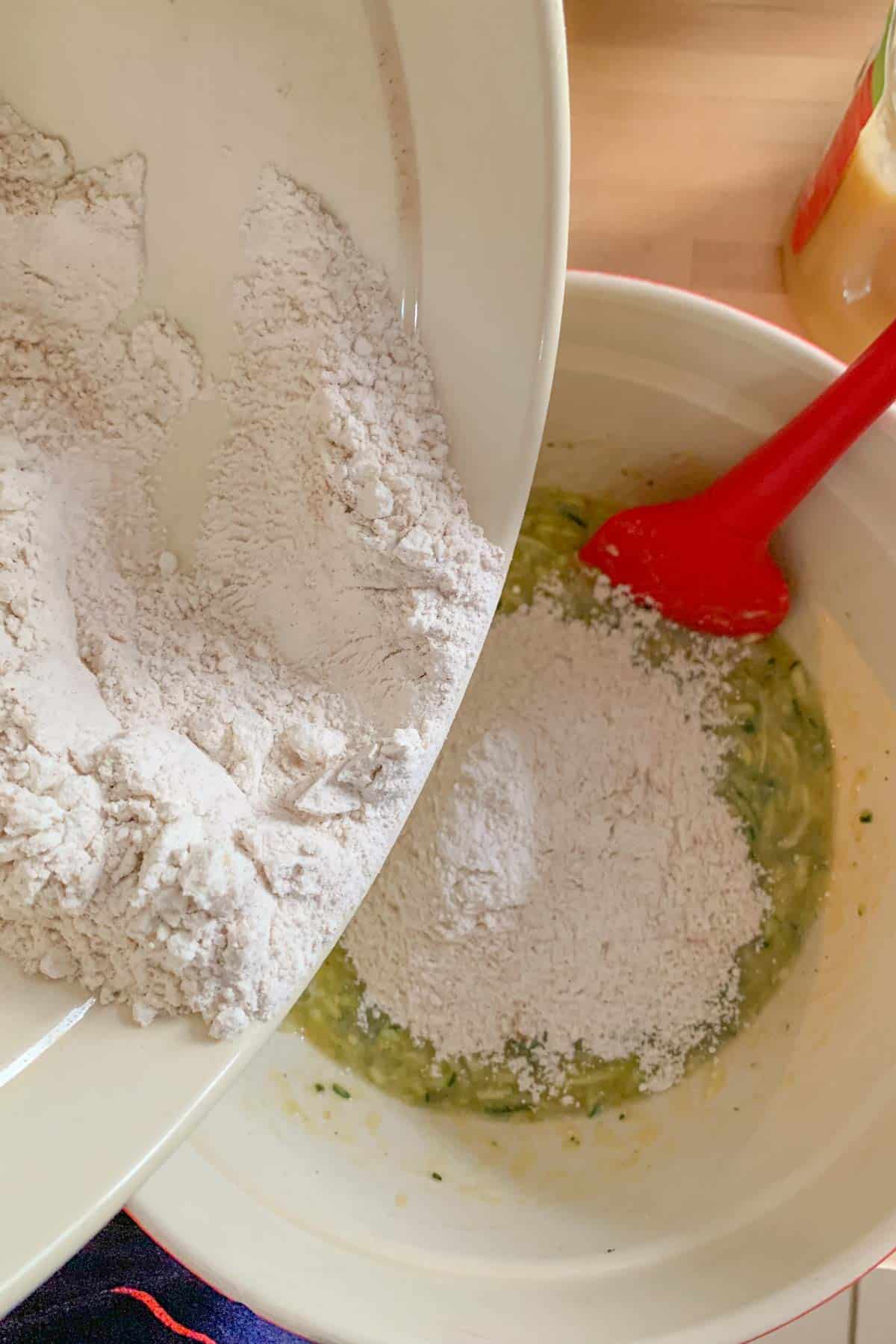 adding dry ingredients to zucchini bread batter